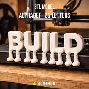 Puede incluir: Letras blancas impresas en 3D que deletrean "BUILD" con pies adjuntos. La imagen incluye el texto "STL MODEL ALPHABET 26 LETTERS" y "DIGITAL PRODUCT". Las letras están sobre una superficie de madera, con una impresora 3D en el fondo.