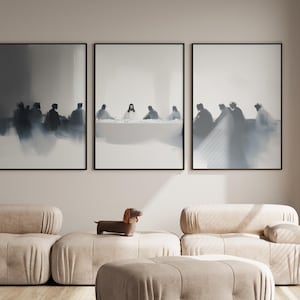 May include: Three framed art prints depicting a blurred, monochromatic scene of people seated at a table. The artwork is displayed above a beige sectional sofa with a dachshund figurine.
