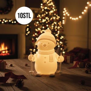 Puede incluir: Una lámpara con forma de muñeco de nieve brillante, con sombrero, bufanda y bastones de esquí. La lámpara tiene una cara sonriente y detalles de botones. El texto "10STL" está en un círculo blanco. El fondo incluye un árbol de Navidad y una chimenea.