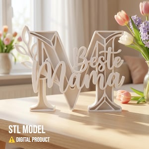 Puede incluir: Un letrero decorativo color crema con forma de la letra "M" con las palabras "Beste Mama" en escritura cursiva. El letrero tiene un diseño floral en el lado izquierdo y se muestra sobre una mesa de madera. Las palabras "STL MODEL" y "DIGITAL PRODUCT" están en la parte inferior.