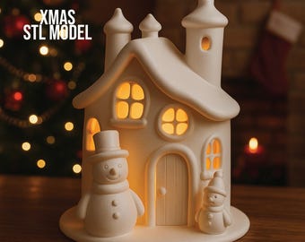 May include: A white ceramic Christmas house with a snowman and a smaller snowman figurine. The house has lit windows and a chimney. The text "XMAS STL MODEL" is visible on the left side of the image. The house is on a wooden surface.