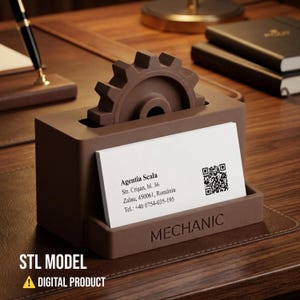 May include: A brown matte business card holder featuring a gear-shaped top element and the word MECHANIC embossed on the front. A white business card for Agentia Scala with an address, phone number, and QR code is displayed in the holder slot.