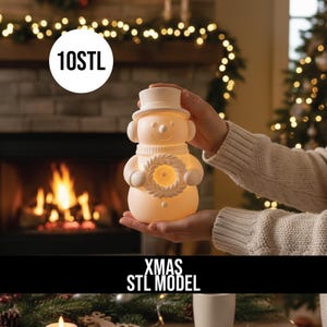 May include: A snowman-shaped lamp with a top hat, scarf, and wreath design. The lamp is lit, emitting a warm glow. The text "10STL" is in a white circle, and "XMAS STL MODEL" is below the lamp.