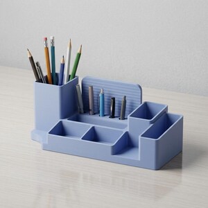 May include: A light blue desk organizer with multiple compartments for pens, pencils, and other office supplies. The organizer has a rectangular shape with various sized slots and a vertical section for holding writing utensils. Pencils and pens are visible.