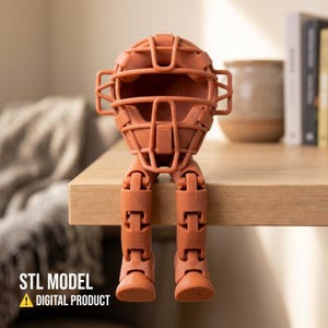 May include: A terracotta-colored, 3D-printed figure of a football helmet with articulated legs. The figure is sitting on the edge of a wooden surface. The text "STL MODEL" and "DIGITAL PRODUCT" are displayed at the bottom.