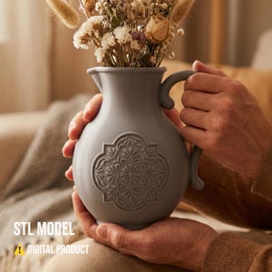 Op de afbeelding: Een grijze decoratieve vaas met een handvat en een bloemmotief, gevuld met gedroogde bloemen. De vaas wordt met beide handen vastgehouden. De tekst "STL MODEL" en "DIGITAL PRODUCT" staan onderaan.
