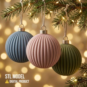 May include: Three spherical Christmas ornaments with a vertical ribbed texture, coloured in muted blue, dusty pink, and olive green. Each ornament features a metallic silver cap and a hanging string. Text reads: STL MODEL DIGITAL PRODUCT.