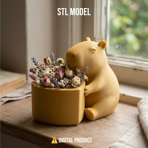 May include: A mustard-yellow capybara-shaped planter holding a small, hexagonal pot filled with dried flowers. The planter is on a wooden surface near a window. The text "STL MODEL" and "DIGITAL PRODUCT" are visible.