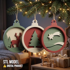 May include: Three circular Christmas ornaments featuring layered cutouts. The first is green with a red deer and trees. The second is white with a red background and a green tree. The third is red with a green background and a white shooting star.