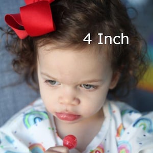May include: A bright red hair bow with a smooth, solid-colored fabric finish. The bow is styled in a classic multi-loop design and is labeled with the text 4 Inch, indicating its size in the imperial system for this hair accessory.