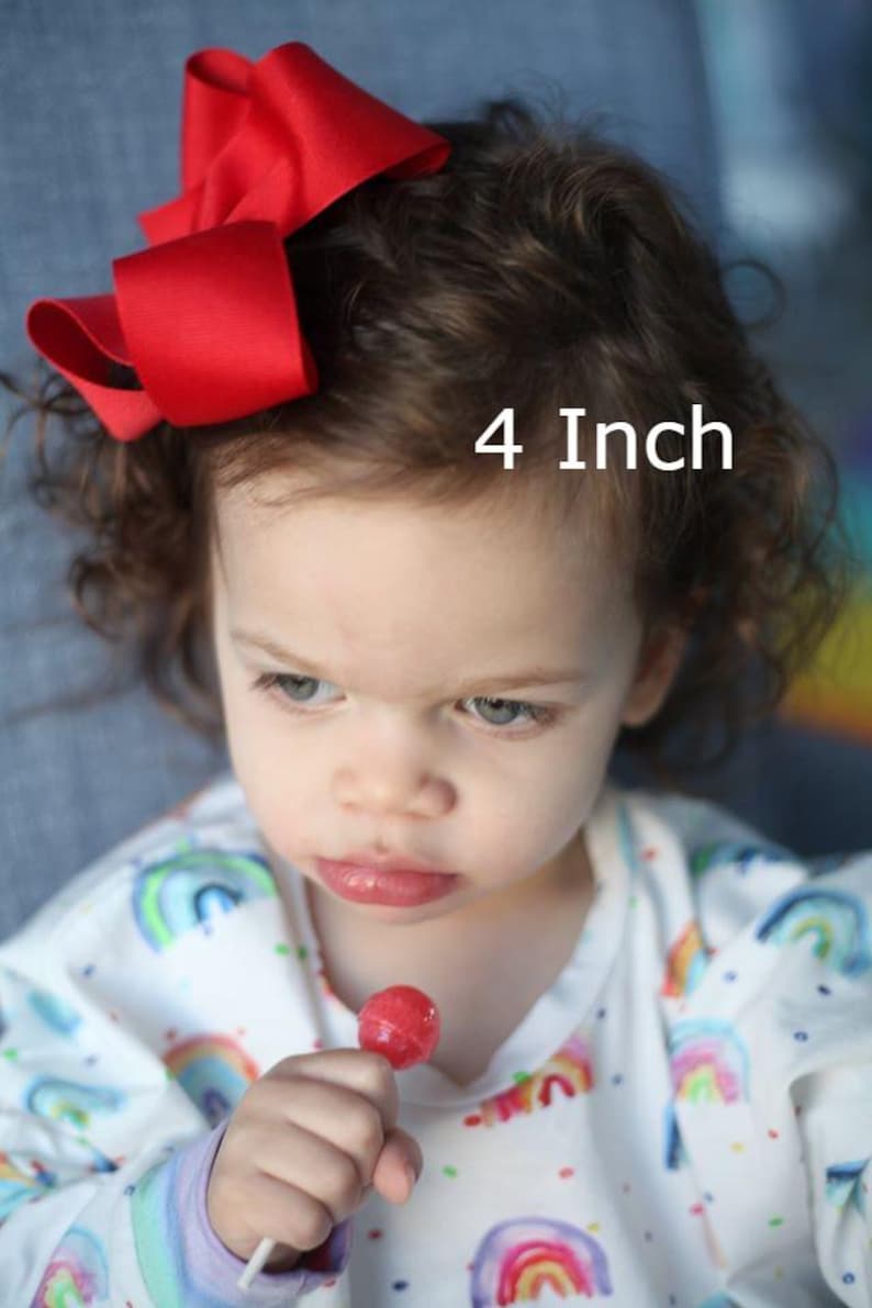 May include: A bright red hair bow with a smooth, solid-colored fabric finish. The bow is styled in a classic multi-loop design and is labeled with the text 4 Inch, indicating its size in the imperial system for this hair accessory.