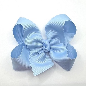 May include: A light blue hair bow made of ribbed grosgrain ribbon. The bow features multiple loops with scalloped edges, creating a layered, voluminous appearance. The center is gathered with a small knot of the same light blue ribbon material.
