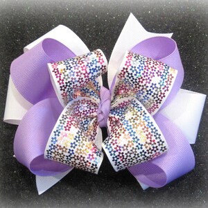 May include: A large purple and white bow with a white center and a colorful floral pattern. The bow is made of ribbon and has a shiny finish.