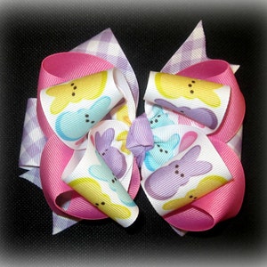 Peut inclure: Un n&oelig;ud rose, blanc et violet avec un motif Peeps jaune pastel, bleu et violet. Le n&oelig;ud est fait de ruban et a un motif &agrave; carreaux au dos.