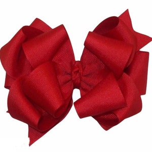 May include: A large, red, fabric bow with a ruffled texture. The bow is tied in the centre and has a loop on each side.