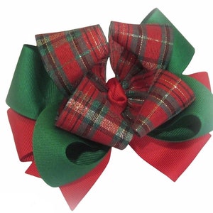 May include: A red and green plaid hair bow with gold glitter. The bow is made of two layers of ribbon, with the top layer being plaid and the bottom layer being solid green.