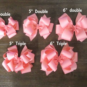 Puede incluir: Una colecci&oacute;n de lazos para el pelo rosas de varios tama&ntilde;os y estilos. Los lazos var&iacute;an entre 10 y 15 cm, con dise&ntilde;os de doble y triple lazo. Las etiquetas de texto indican el tama&ntilde;o y el estilo de cada lazo.