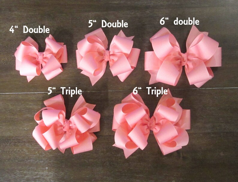 Puede incluir: Una colecci&oacute;n de lazos para el pelo rosas de varios tama&ntilde;os y estilos. Los lazos var&iacute;an entre 10 y 15 cm, con dise&ntilde;os de doble y triple lazo. Las etiquetas de texto indican el tama&ntilde;o y el estilo de cada lazo.