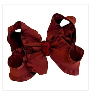 May include: A deep burgundy hair bow featuring a ruffled edge design. The fabric is gathered in the center with a matching knot detail, creating a voluminous, multi-layered appearance with soft, rounded loops on both sides of the central knot.