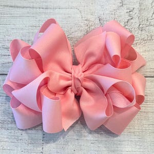May include: A large, pink, satin bow with a centre loop. The bow is made of multiple layers of ribbon and has a soft, fluffy texture.
