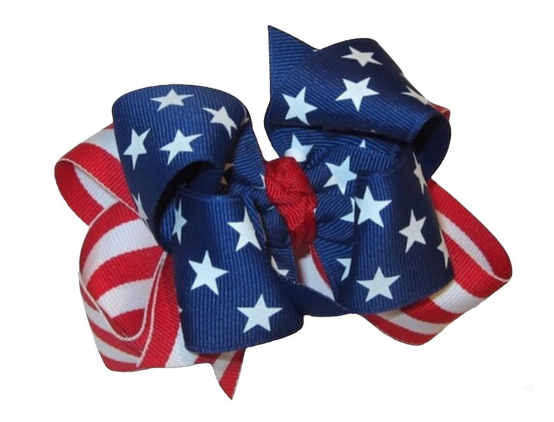 May include: A red, white, and blue ribbon bow with a star pattern. The bow is made of two different ribbons, one with red and white stripes and the other with blue and white stars.