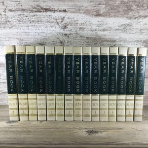 May include: A collection of vintage yearbooks, each with a cream-colored spine and a dark green cover. The spines display the text "YEAR BOOK" in gold lettering, with the years 1967 to 1981 printed below.