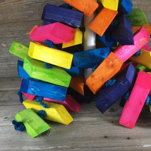 May include: A colorful wooden toy for pets, made of brightly colored blocks connected by rope. The blocks are painted in shades of blue, green, yellow, orange, and pink.