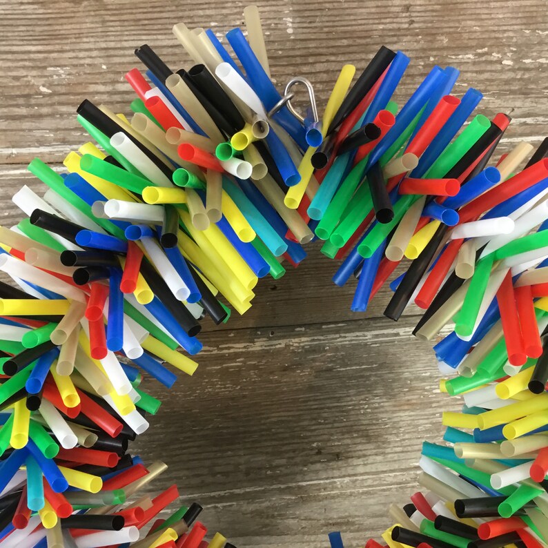Pu&ograve; includere: Una ghirlanda colorata realizzata con cannucce da bere in plastica di colore rosso, giallo, blu, verde, nero e bianco. La ghirlanda &egrave; legata insieme con un anello di metallo argentato.