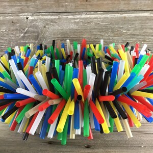 Pu&ograve; includere: Una ghirlanda colorata realizzata con una variet&agrave; di cannucce di plastica per bere. Le cannucce sono disposte in un motivo circolare e sono tenute insieme da un adesivo trasparente. La ghirlanda &egrave; un mix vibrante di cannucce rosse, gialle, blu, verdi, nere e bianche.