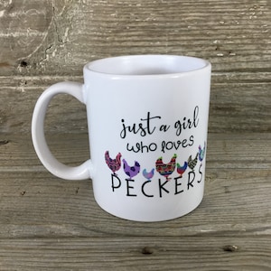 May include: White ceramic mug with a black design that says "just a girl who loves peckers" with a row of colorful chickens below the text.