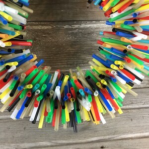 Pu&ograve; includere: Una ghirlanda fatta con cannucce di plastica colorate. Le cannucce sono disposte in un cerchio e tenute insieme da un filo o una corda. La ghirlanda &egrave; una decorazione allegra e vivace che sarebbe perfetta per una festa estiva o una cameretta per bambini.