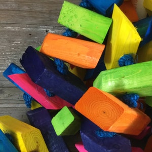 May include: A colorful wooden toy with brightly colored blocks connected by blue rope. The blocks are painted in shades of blue, green, yellow, orange, and pink.