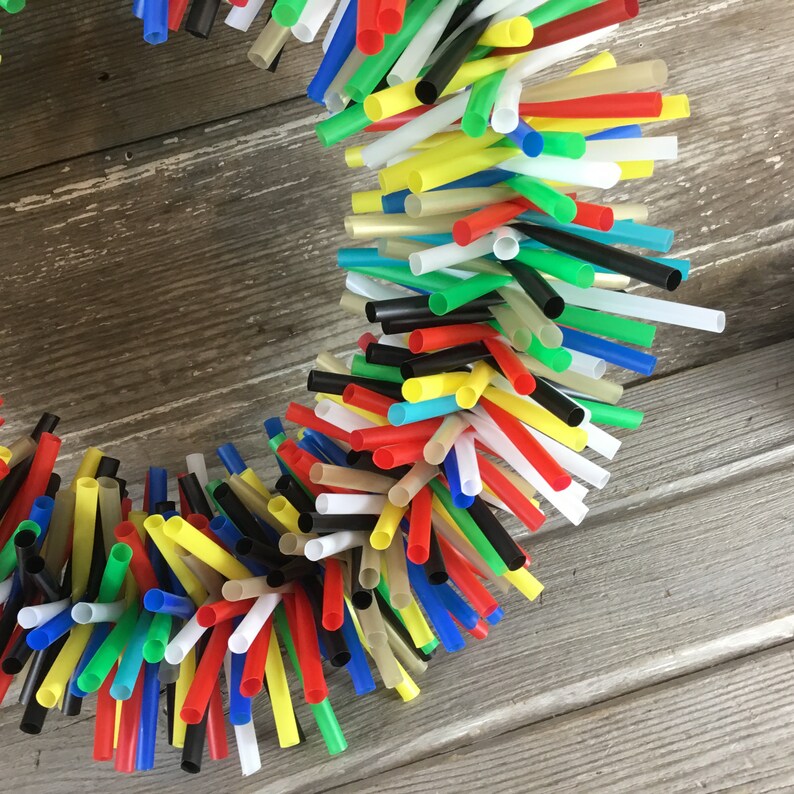 Pu&ograve; includere: Una ghirlanda colorata realizzata con cannucce da bere di vari colori, tra cui rosso, giallo, blu, verde e nero. Le cannucce sono disposte in un motivo circolare, creando una decorazione festosa e fantasiosa.