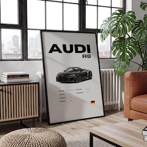 May include: Black framed poster featuring an Audi R8 convertible. The poster has the word "AUDI" in large black letters, with "R8" below. Below the car image are specifications and a German flag.