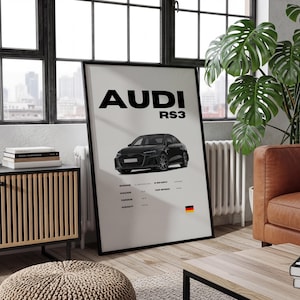 May include: A framed poster featuring a black Audi RS3 car illustration. The poster has the word "AUDI" above the car and "RS3" below it. Below the car are specifications and the German flag.