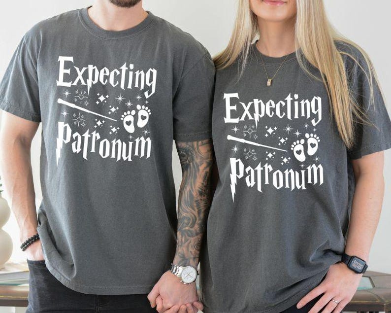 May include: Two gray t-shirts with the text "Expecting Patronum" and a graphic of a wand and baby footprints.