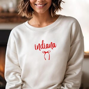 コケットな雰囲気とユニセックスフィットのキュートなインディアナ州プライドスウェットシャツ、キュートなリボンクルーネック、インディアナ州と中西部の女の子向けの州スウェットシャツ
