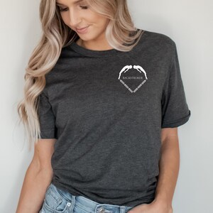 May include: A dark heather grey t-shirt with a white graphic of two swimmers forming a heart shape with the text "BACKSTROKER" inside the heart.