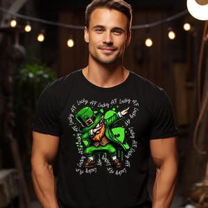 Könnte beinhalten: Schwarzes T-Shirt mit einem grünen Leprechaun, der dabbt. Der Leprechaun trägt einen grünen Hut und Mantel sowie braune Schuhe. Der Text "Lucky AF" ist kreisförmig um den Leprechaun geschrieben.