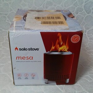May include: A red Solo Stove Mesa tabletop fire pit in its original packaging. The box features the Solo Stove logo, product name, and a graphic of the fire pit with flames. The box also highlights features like easy use and low smoke.