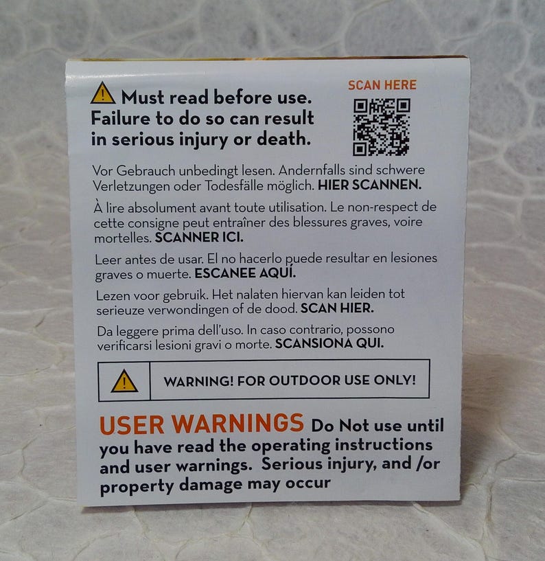 May include: A white and yellow warning label with text in multiple languages. The label warns of serious injury or death if instructions are not followed. Includes a QR code and the text: "WARNING! FOR OUTDOOR USE ONLY!"