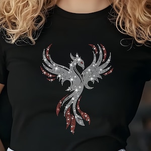 May include: A black t-shirt featuring a rhinestone phoenix design. The phoenix is silver with red accents.