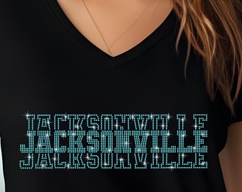 May include: Black v-neck t-shirt with a sparkly blue rhinestone design that reads "JACKSONVILLE".