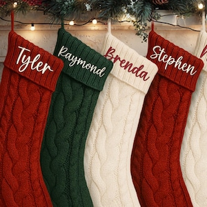 May include: Five cable-knit Christmas stockings in red, green, and cream colors hang from a fireplace mantel. Each stocking is personalized with a name in a complementary color: "Tyler", "Raymond", "Brenda", "Stephen", and "Nicole".