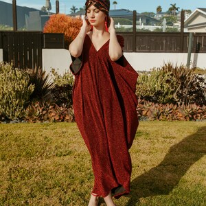 Shimmering, metallic crimson red caftan dress featuring v-neck at front and back.