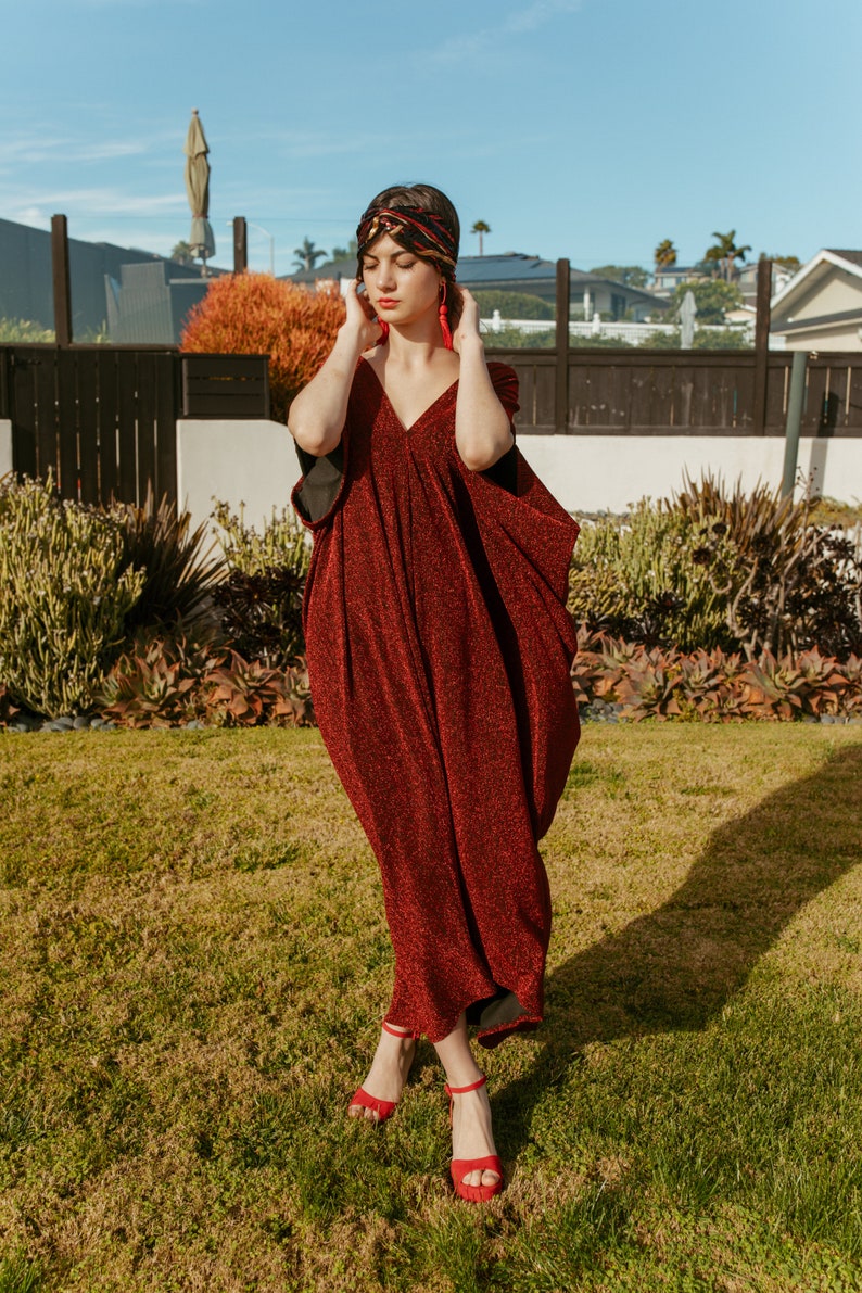 Shimmering, metallic crimson red caftan dress featuring v-neck at front and back.