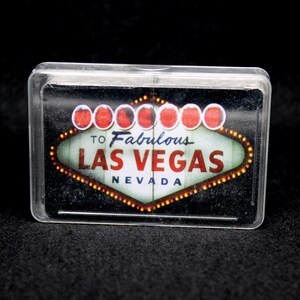 May include: A clear plastic card holder with a black and white image of the "Welcome to Fabulous Las Vegas, Nevada" sign with red light bulbs.