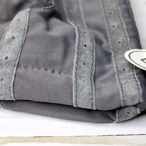 May include: A white ceramic mug with a black handle and the text "But First, Coffee" in a bold, black font. The mug is set against a blurred background, suggesting a cosy setting.