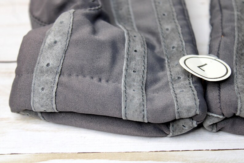 May include: A white ceramic mug with a black handle and the text "But First, Coffee" in a bold, black font. The mug is set against a blurred background, suggesting a cosy setting.