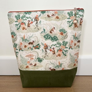 May include: A rectangular fabric pouch with a zip closure featuring a light-coloured print of mice, frogs, snails, and mushrooms in a garden setting with text reading Radish 5c. The bottom section is made of solid dark olive green corduroy fabric.